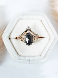 an engagement ring with a black diamond surrounded by feathers