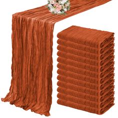 a stack of orange cloths with a bouquet on top