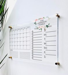 a calendar hanging on the side of a white wall next to a potted plant