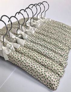 four pieces of cloth hanging on clothes pins with white bows and green leaves printed on them