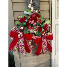 a red and green christmas wreath hanging from the side of a house with numbers on it