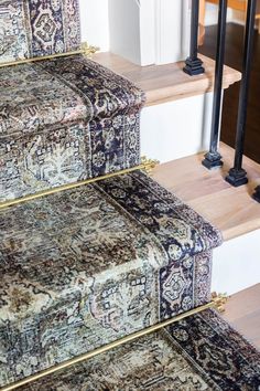 a carpeted stair case with an ornate design on the top and bottom, along with other rugs