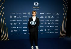 a man standing in front of a blue wall holding an award