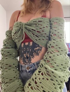 a woman wearing a green crochet sweater with long sleeves and an open back