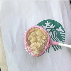 a cupcake with pink frosting and a starbucks logo on it is sitting in a paper bag