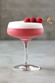 a pink drink with raspberries on the rim