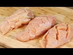 three pieces of raw chicken sit on a cutting board