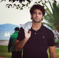 a man is standing in the grass with his hand on his shirt and holding something