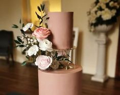 a three tiered pink wedding cake with flowers on top