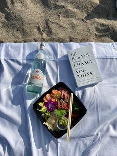 a plate of food with chopsticks next to a bottle of water on a blanket