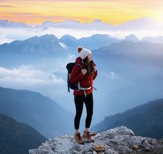 a man and woman standing on top of a mountain looking out at the valley below