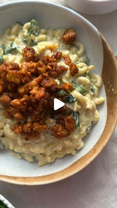 a white bowl filled with pasta and meat on top of a table next to vegetables