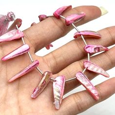 a person is holding some pink and silver pins