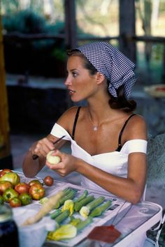 a woman sitting at a table with apples and vegetables