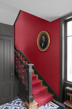 a red room with stairs and a portrait on the wall