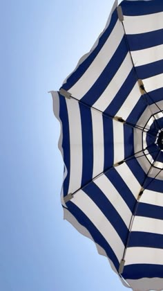 an open umbrella with blue and white stripes on the top, against a clear blue sky