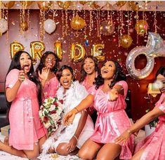 a group of women in pink dresses posing for a photo with balloons and confetti