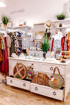 the inside of a clothing store with baskets and purses on display in front of it