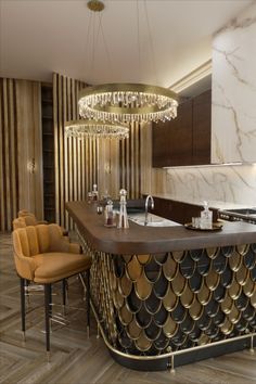 an elegant kitchen with gold accents and marble counter tops, along with two chairs in front of the bar