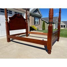 a wooden bed frame in front of a house