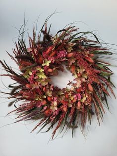 a wreath with red flowers and green leaves on the front is hanging against a white wall