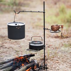 an outdoor cooking area with fire, pot and kettle