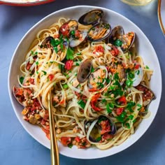 a bowl of pasta with clams and bread on the side