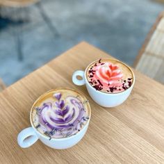 two cups filled with liquid sitting on top of a wooden table