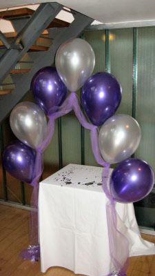 purple and silver balloons are arranged on a table