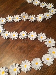 white daisies are arranged in the shape of a heart on a wooden table top