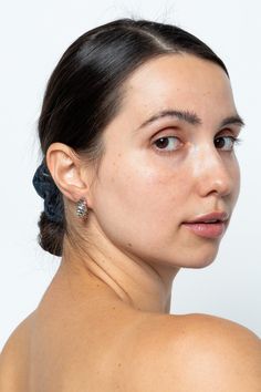 a young woman with freckles on her shoulder looking off to the side while wearing earrings