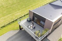 two people are sitting on the deck of a house with grass and trees in the background