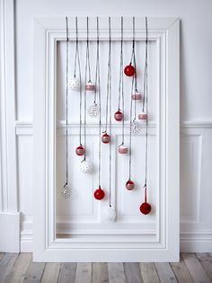 a white frame with red and white ornaments hanging from it's sides on a wooden floor