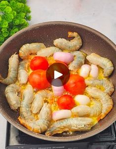 a pan with shrimp and tomatoes cooking on the stove