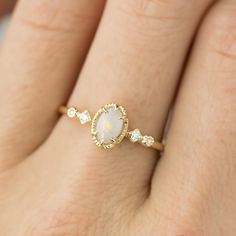 a woman's hand wearing a gold ring with an opal and diamond band