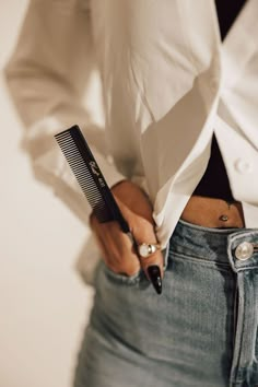 a close up of a person holding a comb and scissors in their hands while wearing jeans