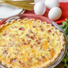 an egg and bacon quiche in a glass pie dish on a red tablecloth