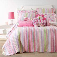 a bed with pink and green striped bedspread, pillows and stuffed animals on it