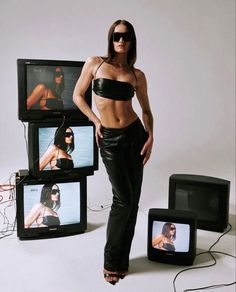 a woman standing in front of televisions with her hands on her hips and legs crossed