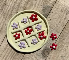 a white plate with red and purple flowers on it next to two small pieces of cake