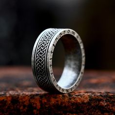 a wedding ring with an intricate design on it sitting on top of a piece of wood