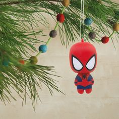 a spiderman ornament hanging from a pine tree