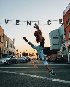 a person jumping in the air on a city street with cars and buildings behind them