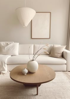 a living room with a white couch, coffee table and two vases on it