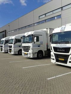 a row of white trucks parked in front of a building