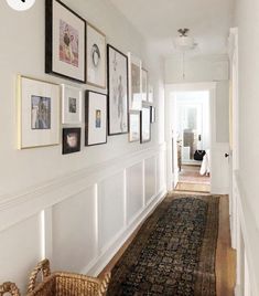 a long hallway with pictures on the wall and a rug in front of an open door