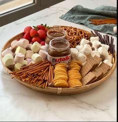 a platter filled with crackers, marshmallows, pretzels and strawberries