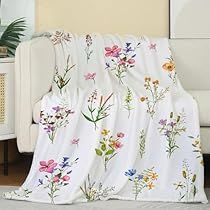 a white couch sitting next to a window covered in a blanket with flowers on it