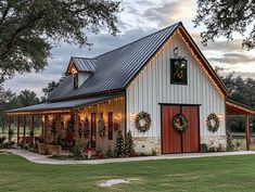 a white barn with christmas lights and wreaths on it