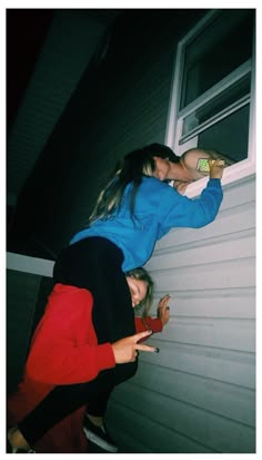 two girls leaning against the side of a house